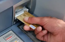 Main tenant une carte bancaire devant un distributeur (© J-S. Evrard / AFP)